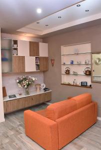 a living room with an orange couch and shelves at B&B Cava Rossa in Monsummano