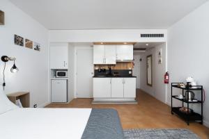 um quarto com uma cama e uma cozinha com armários brancos em Cantinho do Mar em Portimão
