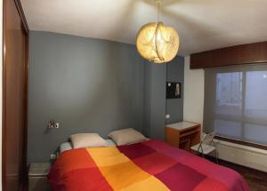 um quarto com uma cama com um cobertor colorido em Apartamento zona Ria do Burgo em La Coruña