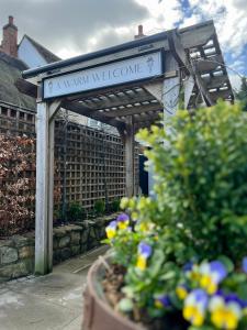 un cartel en un jardín con flores en una olla en The Lion, Tredington en Shipston on Stour