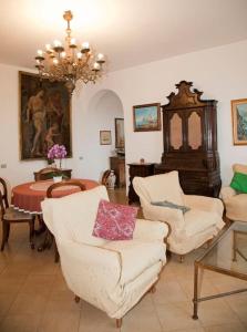 una sala de estar con sillas blancas y una lámpara de araña. en Appartamento in villa vista mare en Ischia