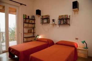 two beds in a room with a book shelf at Appartamento in villa vista mare in Ischia