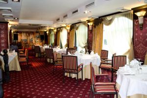 uma sala de jantar com mesas e cadeiras brancas em Shiny River Hotel em Ustʼ-Kamenogorsk