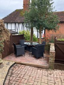 a patio with a table and chairs in a backyard at The Smithy Cottage in Chilham