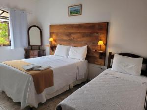 a hotel room with two beds and a mirror at Pouso Mariazinha in Tiradentes