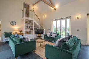 a living room with two green couches and a tv at Chestnut Barn, North Norfolk with private hot tub & close to beaches in Norwich