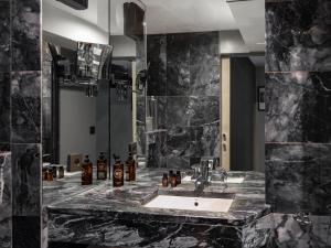 La salle de bains est pourvue d'un lavabo et d'un grand miroir. dans l'établissement Hôtel Edgar & Achille, à Paris