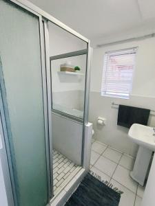 a bathroom with a glass shower and a sink at NoulAnouk's Corner in Cape Town