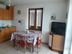 uma cozinha com uma mesa com cadeiras e uma televisão em Appartamento Cologna em Castelfondo