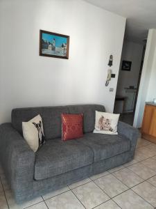 um sofá cinzento sentado numa sala de estar com almofadas em Appartamento Cologna em Castelfondo