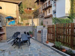 eine Terrasse mit einem Tisch, Stühlen und einem Zaun in der Unterkunft La corte in Vezzo