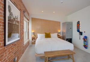 a bedroom with a white bed and a brick wall at Venice V Hotel in Los Angeles