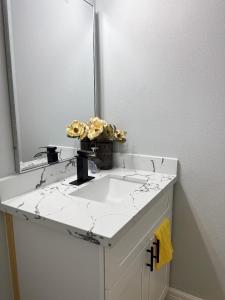 a bathroom sink with a mirror and flowers on it at 77072 New remodeled Cute Townhome SW in Houston