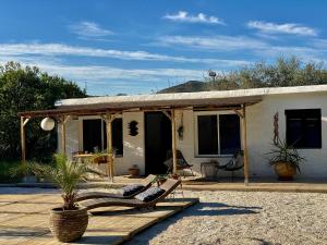 a house with a porch with lounge chairs in front of it at Casita Azahar Andalucia in Alhaurín de la Torre