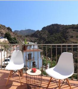 2 sillas blancas y una mesa en el balcón en Apartamento Navas, en Frigiliana