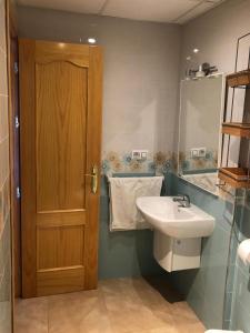 La salle de bains est pourvue d'un lavabo et d'une porte en bois. dans l'établissement Apartamento Navas, à Frigiliana