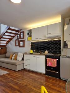 una cocina con armarios blancos y un sofá en una habitación en STUDIO 8CERRO 4Pax en la mejor zona de Córdoba Arg en Córdoba
