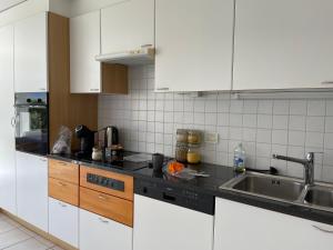 una cocina con armarios blancos y fregadero en Locarno-Muralto: Raggio di Sole, en Muralto