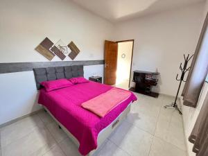 a bedroom with a large bed with a pink blanket at Aconchego e tranquilidade 1 in Bonito