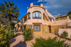 a house with a palm tree in front of it at Villa Markus - Plusholidays in Calpe