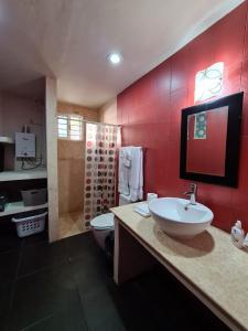 baño con lavabo, aseo y paredes rojas en Palapa rooftop w/ beach views! Cozy Casa Dumas, en Chuburná