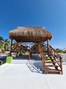 una silla, una sombrilla de paja y escaleras en una playa en Palapa rooftop w/ beach views! Cozy Casa Dumas, en Chuburná