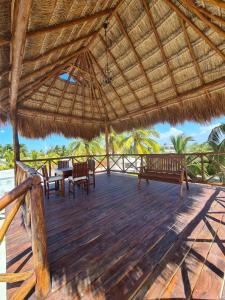 ChuburnáにあるPalapa rooftop w/ beach views! Cozy Casa Dumasの茅葺き屋根の木製デッキ(ベンチ付)