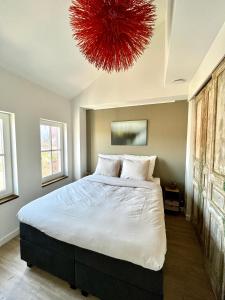 a bedroom with a large bed with a red chandelier at B&B Logement 't Slikje in Groede