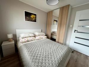 um quarto com uma cama com um edredão branco em Apartament Błękitna em Gdynia