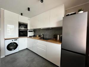 uma cozinha com armários brancos e uma máquina de lavar roupa em Apartament Błękitna em Gdynia