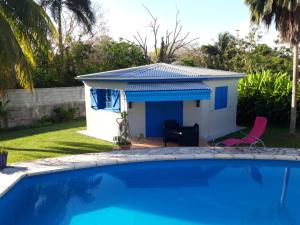 a cottage with a swimming pool in front of a house at Idéal pour séjour professionnel ou touristique in Baie-Mahault