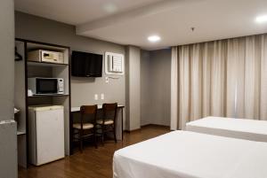 a hotel room with two beds and a microwave and a kitchen at Master Express Cidade Baixa - Próximo à UFRGS e à Santa Casa in Porto Alegre