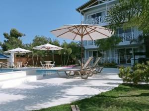 a patio with chairs and umbrellas next to a house at Oasis Tolú Hotel Boutique in Tolú