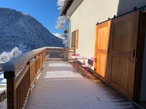 une clôture en bois à côté d'une maison recouverte de neige dans l'établissement Le Sarana : 75m2, calme, belle vue avec terrasse., à Les Deux Alpes