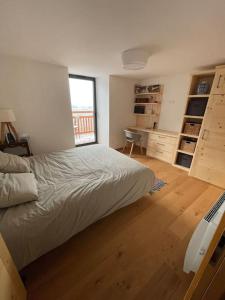 - une chambre avec un lit, un bureau et une fenêtre dans l'établissement Le Sarana : 75m2, calme, belle vue avec terrasse., à Les Deux Alpes