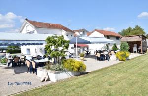 un patio con mesas y sillas frente a un edificio en Logis Hôtel Restaurant La Vraine en Gironcourt-sur-Vraine