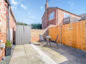 un patio con 2 sillas y una mesa frente a una valla en Maceys Cottage - Uk42146 en North Somercotes