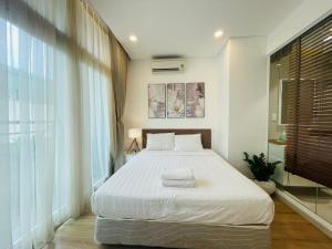 - une chambre avec un grand lit et une grande fenêtre dans l'établissement City By Night Ben Thanh Apartments, à Hô-Chi-Minh-Ville