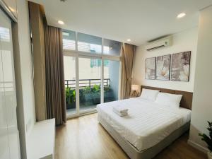 - une chambre avec un lit blanc et une grande fenêtre dans l'établissement City By Night Ben Thanh Apartments, à Hô-Chi-Minh-Ville