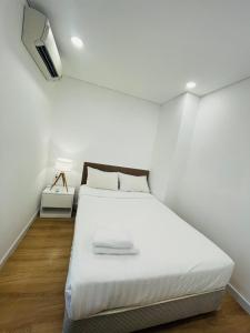 1 dormitorio blanco con 1 cama y TV en City By Night Ben Thanh Apartments en Ho Chi Minh