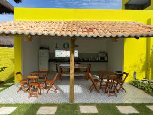 een patio met een tafel en stoelen en een gele muur bij Villa Suites Gostoso - Condomínio Beira-mar in São Miguel do Gostoso