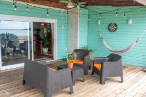 un patio con sillas, mesas y una hamaca en Casa del Fuego - Caribbean Beachfront Magic!, en Bocas Town