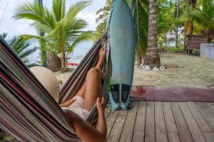 a woman laying in a hammock next to a surfboard at Casa del Fuego - Caribbean Beachfront Magic! in Bocas del Toro