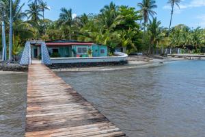a house on the beach with a wooden walkway at Casa del Fuego - Caribbean Beachfront Magic! in Bocas del Toro