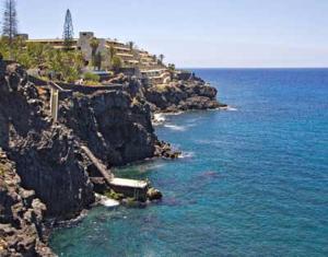 una costa rocciosa con una casa e l'oceano di Tenerife Primavera ad Arona