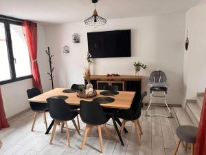 a dining room with a table and chairs and a television at Le phare in Yport