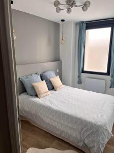 Un dormitorio con una cama con almohadas azules y una ventana en Le phare, en Yport