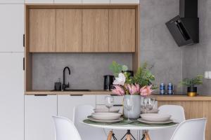a kitchen with a table with plates and flowers on it at Lux Apartment Grzegórzecka Estate Cracow by Renters Prestige in Krakow
