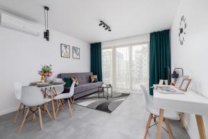 ein Wohnzimmer mit einem Sofa, einem Tisch und Stühlen in der Unterkunft Lux Apartment Grzegórzecka Estate Cracow by Renters Prestige in Krakau