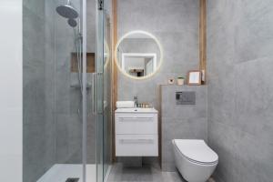ein Bad mit einer Dusche, einem WC und einem Spiegel in der Unterkunft Lux Apartment Grzegórzecka Estate Cracow by Renters Prestige in Krakau